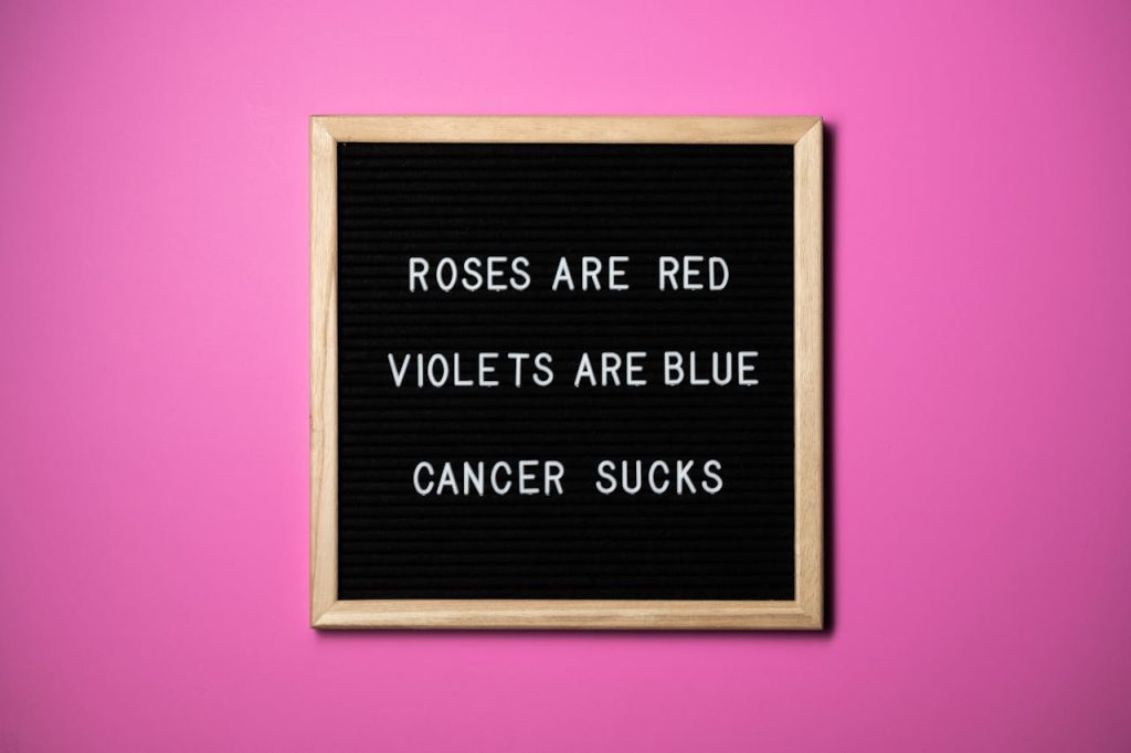 Inspirational letter board with a pink backdrop promoting cancer awareness.